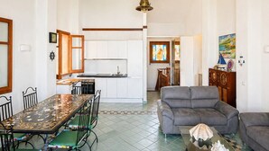 A spacious living area with a dining table, sofas, and a kitchen in the background. - Vacation home facing the sea in Scylla (Scilla)