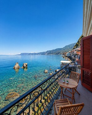 A balcony with a clear view of the sea, a wooden table, and chairs. - Chianalea 31 – Seafront home with two private balconies (Scilla)