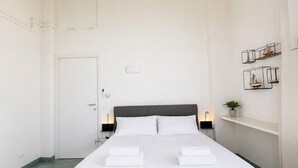 A single bed with a grey headboard, white linens, and two bedside tables with lamps. - Vacation home facing the sea in Scylla (Scilla)