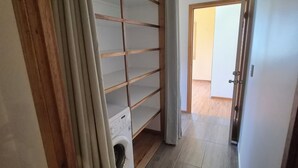 Een wasserij met een wasmachine, een droogrek en een houten plankunit.