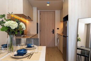 Eine moderne Küche mit Essbereich, Holzschränken, einem Kühlschrank und einem Fernseher.