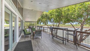 A covered outdoor area with a wooden deck, seating, and a view of the water. - Casa Arroyo Upper Level - Dock, Sleeps 14 (Arroyo City)