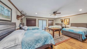 A hotel room with two beds, a ceiling fan, a wooden table, and a mounted deer head on the wall. - Casa Arroyo Upper Level - Dock, Sleeps 14 (Arroyo City)