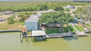 A large building with a flat roof, surrounded by trees and a dock extending into a body of water. - Casa Arroyo Upper Level - Dock, Sleeps 14 (Arroyo City)