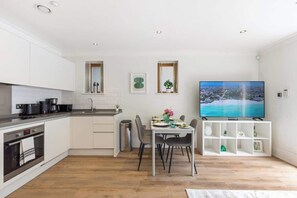 Eine moderne Küche mit Essbereich, einem Fernseher und einem kleinen Fenster.
