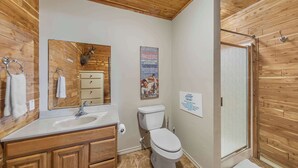 Un bagno con rivestimenti in legno, un lavandino, un WC e una doccia.