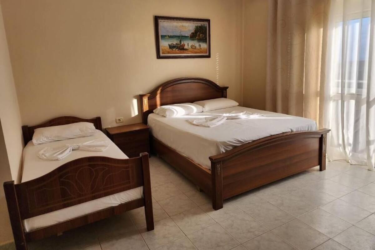 Un dormitorio con una cama doble, una mesita de noche, una silla de madera y un cuadro en la pared.