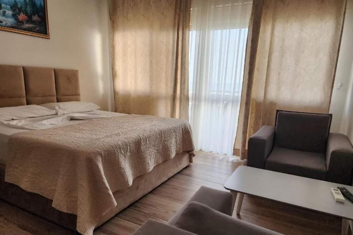 Una habitación de hotel con una cama, un sofá, una mesita y un cuadro en la pared.