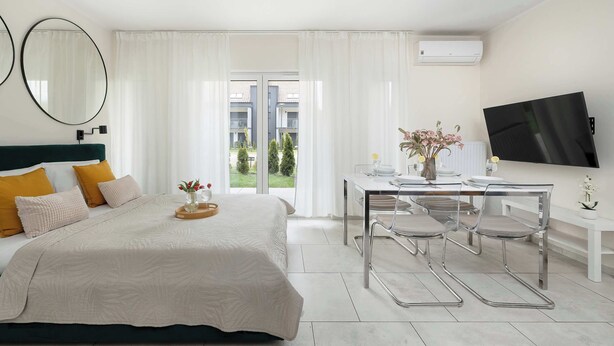 Ein Hotelzimmer mit Bett, Schreibtisch mit Stühlen, Fernseher und Blick ins Freie.