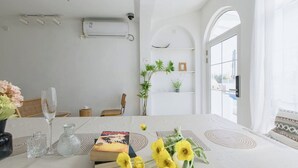 Un comedor con una mesa dispuesta para dos personas, que incluye un libro, un vaso y un jarrón con flores.