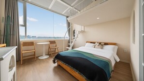 Habitación de hotel con cama, una mesita, una silla, ventana con vistas y balcón.