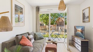 Ein Wohnzimmer mit Sofa, Couchtisch, Fernsehschrank und Blick auf eine Holzhütte durch eine Glastür.