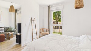 Ein Schlafzimmer mit Bett, Stuhl, einer Leiter und einem Fenster mit Blick ins Freie.