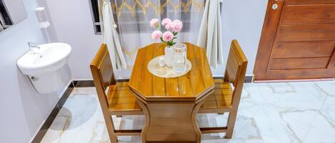 A wooden dining table with chairs, a white sink, and a vase with flowers.