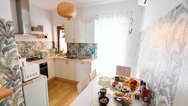 Una cocina moderna con comedor, que incluye estufa, pileta y una mesa con desayuno servido.