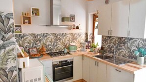 Una cocina moderna con una isla central, horno empotrado, estufa a gas y una lámpara colgante.