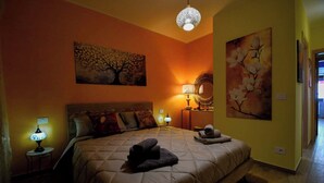Un dormitorio con una cama, dos lámparas de noche, un espejo en la pared y dos cuadros.