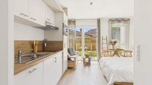 Une chambre d’hôtel compacte comprenant un coin cuisine, un lit, une petite table et une vue sur l’extérieur.
