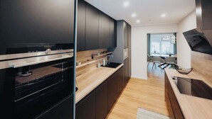 A modern kitchen with dark cabinetry, a wooden countertop, and a built-in oven. - High-quality vacation apartment with sauna and fitness (Tholey)