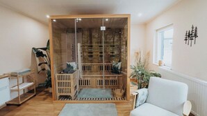A room with a glass partition, a white sofa, a wooden shelf, and a window. - High-quality vacation apartment with sauna and fitness (Tholey)