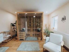 A room with a glass partition, a white sofa, a wooden shelf, and a window. - High-quality vacation apartment with sauna and fitness (Tholey)