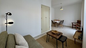 A living room with a sofa, a coffee table, a dining area with a table and chairs, and two pendant lights. - Lagos Design 5 by Homing (Lagos)