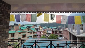 Vista de un pueblo con vibrantes banderas de oración colgadas a través de la calle, edificios con techos verdes y una obra en construcción al fondo.