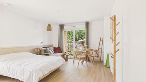 Ein Schlafzimmer mit einem Bett, einem kleinen Tisch mit Stühlen, einer Holzleiter und Blick ins Freie.