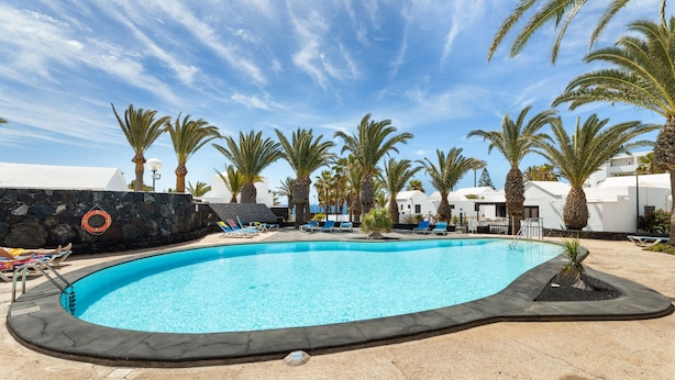 Una piscina con sillas de descanso y palmeras.