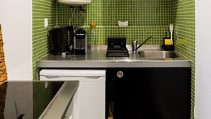 Una cocina compacta con cafetera, tostadora y lavamanos.