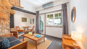 Una habitación con pared de piedra, muebles de madera, una ventana con cortinas y vistas al exterior.