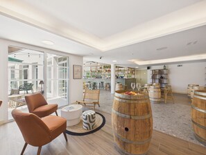 Een ruime kamer met een bar, houten vaten en comfortabele zitplaatsen.