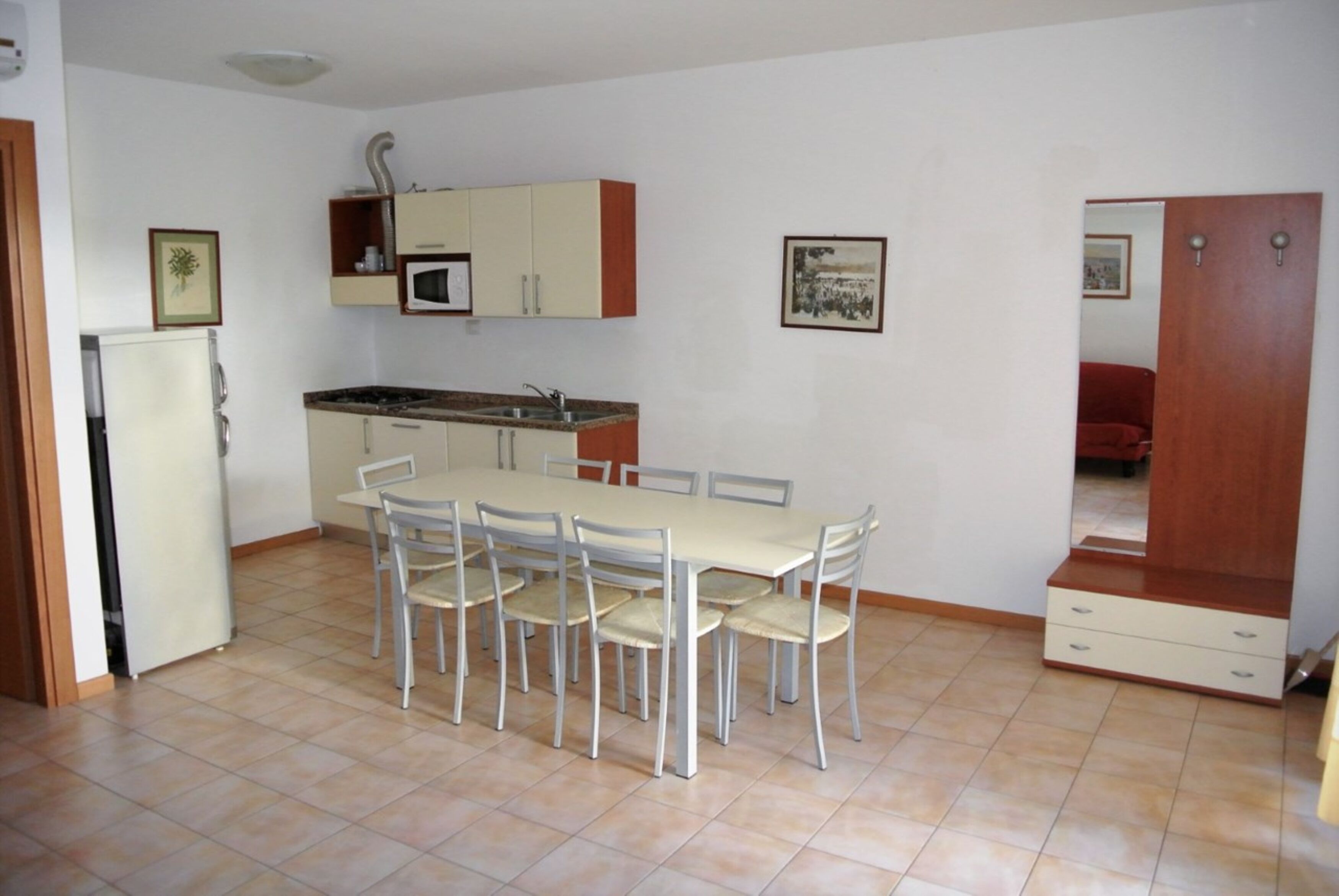 A compact kitchen with a dining table and chairs, a microwave, and a refrigerator.