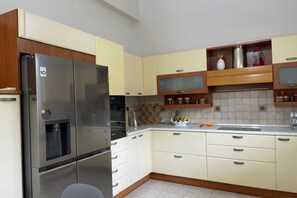 Eine Küche mit einem Edelstahl-Kühlschrank, weißen Schränken, einer Mikrowelle und einer Obstschale auf der Arbeitsfläche.