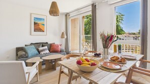 Una habitación luminosa con una mesa de comedor de madera, un sofá y un balcón con vistas.