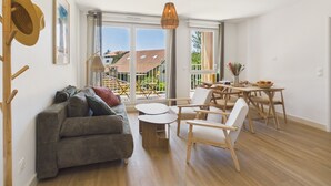 Una sala de estar moderna con sofá, sillas, una mesa de comedor y vistas amplias a través de ventanas grandes.