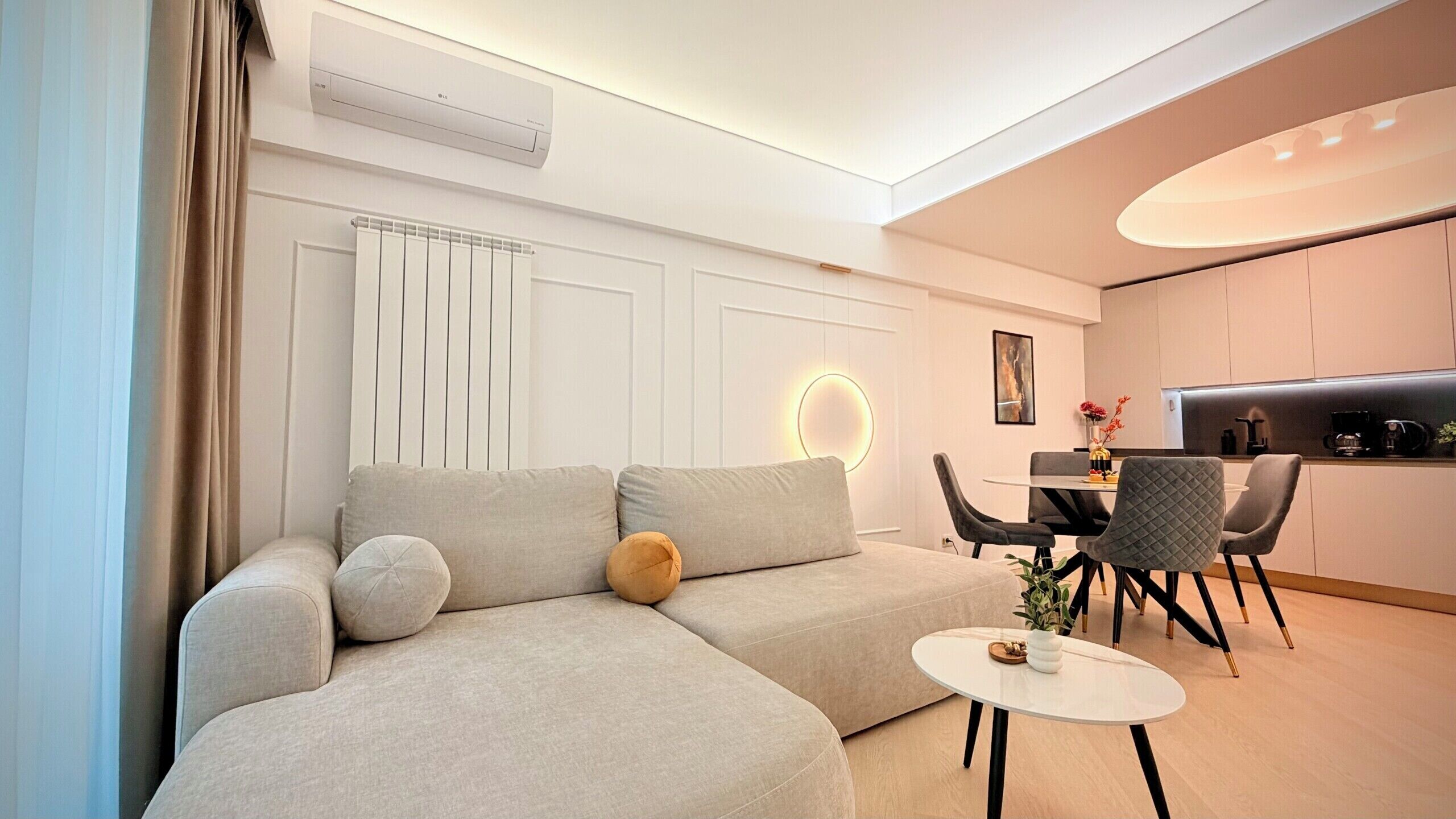 A modern living room with a sectional sofa, a round coffee table, and a dining area with chairs and a table.