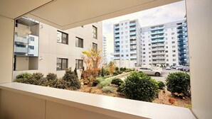 Un edificio moderno con varios pisos, amplias ventanas y un balcón con plantas.