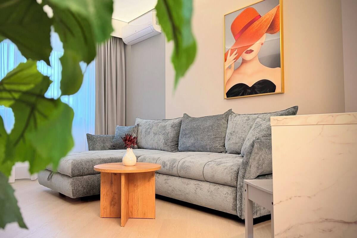 Una sala de estar moderna con un sofá gris, una mesa de centro de madera y un cuadro en la pared.