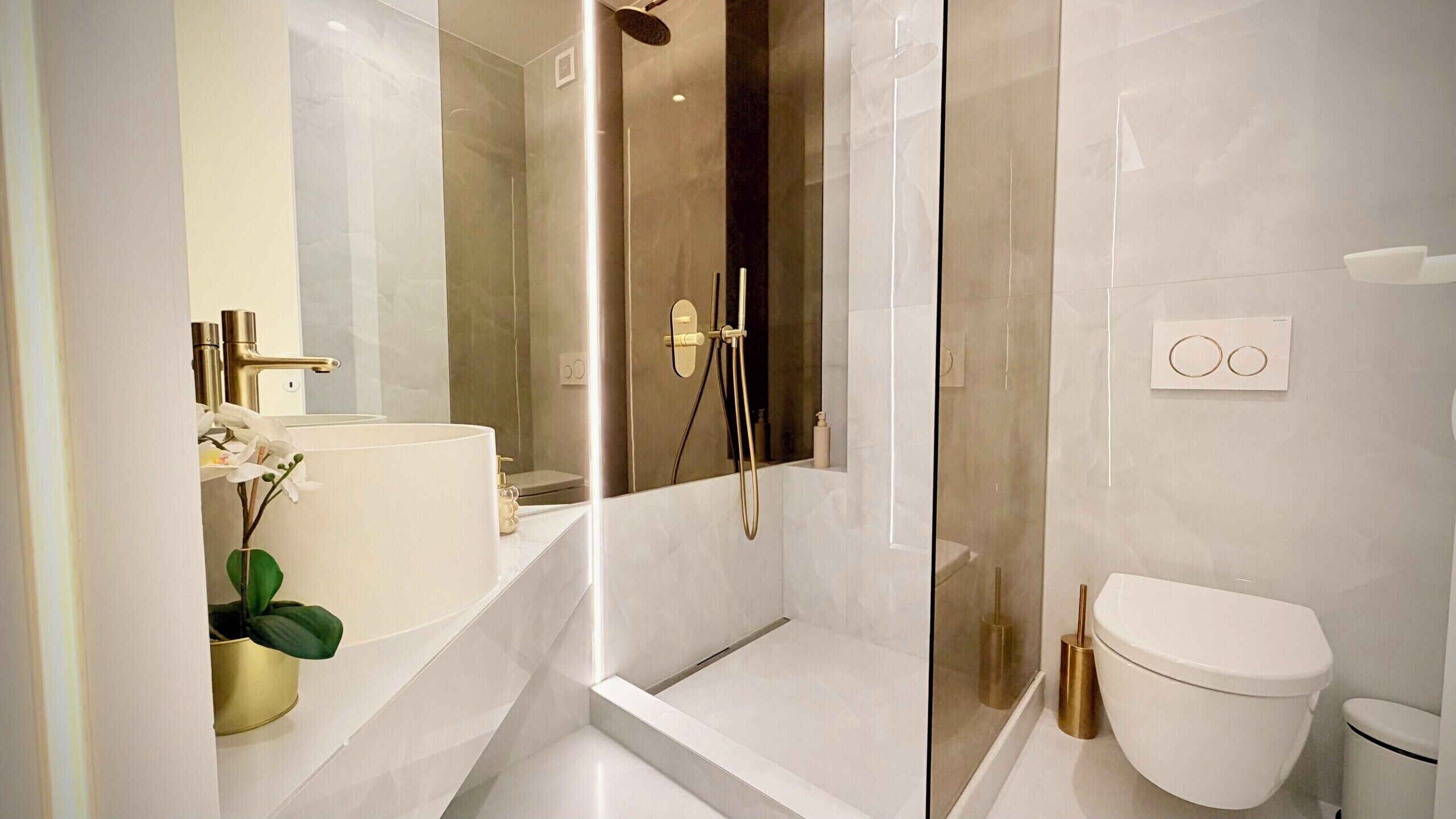 A modern bathroom with a glass-enclosed shower, a white sink, and a toilet.