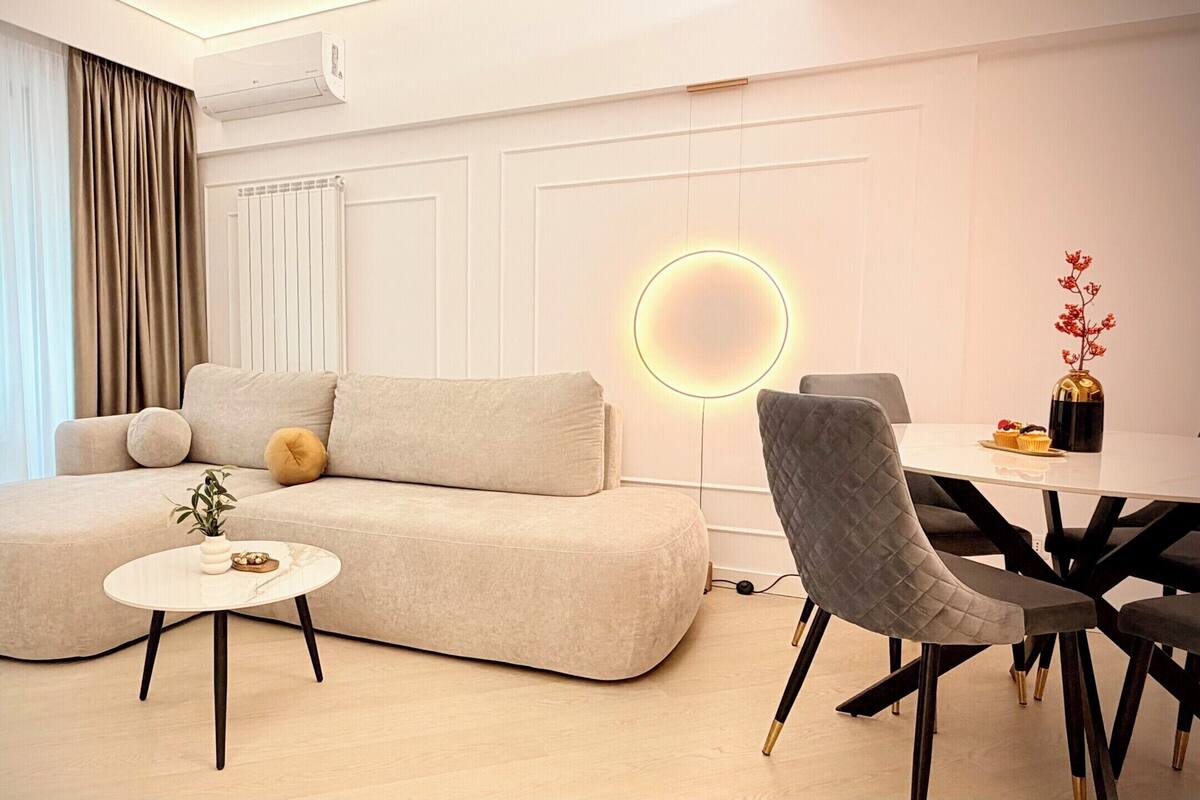 Una sala de estar moderna con un sofá, una mesa redonda de centro y un comedor con mesa y sillas.