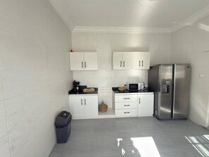 A compact kitchen with white cabinets, a stainless steel refrigerator, and a microwave.