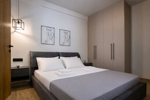 Ein modernes Schlafzimmer mit Bett, Nachttischen, einem Kleiderschrank und zwei Wandbildern.