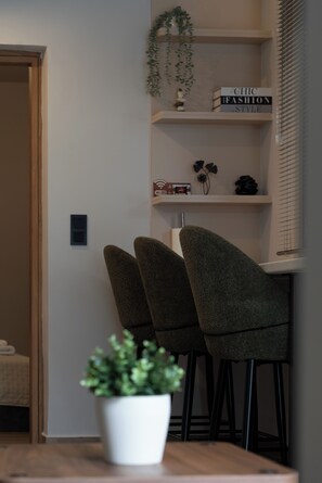 Ein modernes Interieur mit einer Holztür, einer weißen Wand, einem Regal mit Büchern und Dekoration sowie zwei Polsterstühlen.