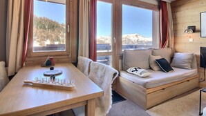 A cozy room with a wooden table, a cushioned bench, and large windows offering mountain views. - Beautiful 2-room apartment for 4 people, balcony, Plagne 1800 (La Plagne 1800)