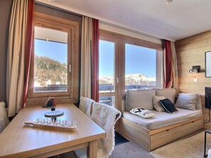 A cozy room with a wooden table, a cushioned bench, and large windows offering mountain views. - Beautiful 2-room apartment for 4 people, balcony, Plagne 1800 (La Plagne 1800)