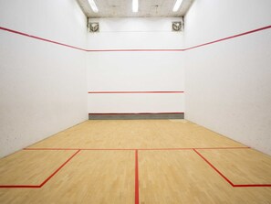 Een squashbaan met houten vloer en rode lijnen.