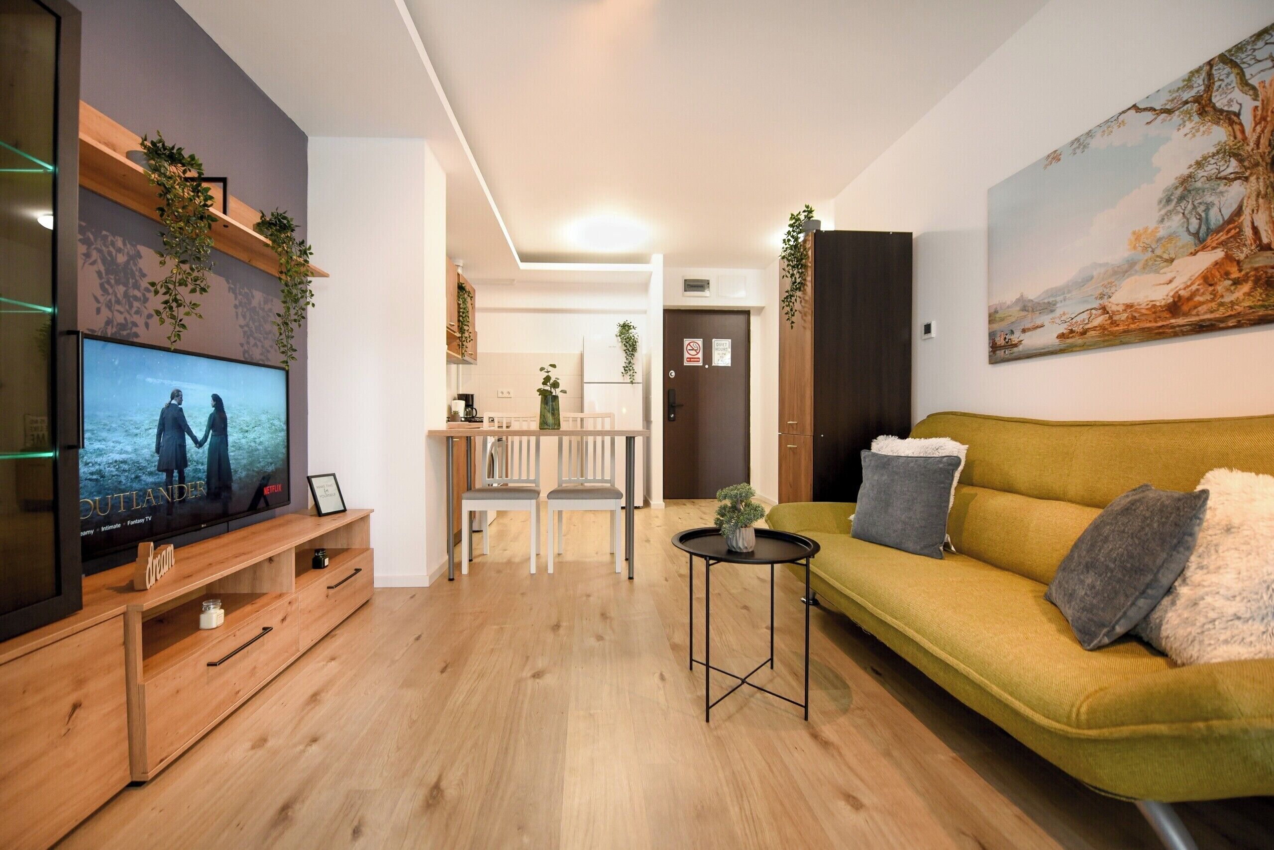 A living room with a TV, sofa, and dining area.