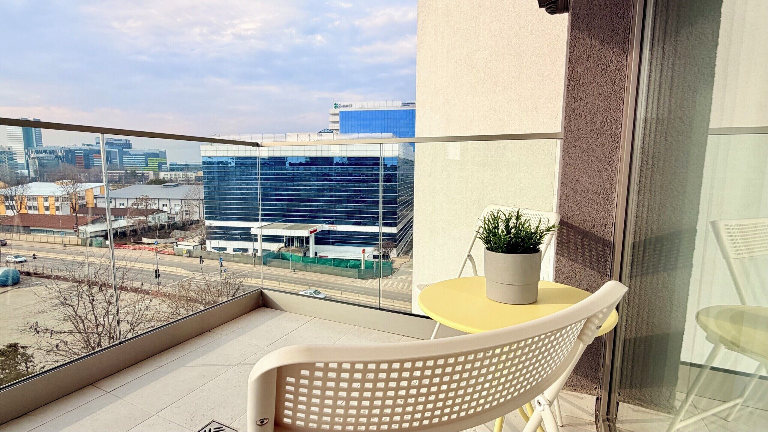A balcony with a chair, a small table, and a potted plant.