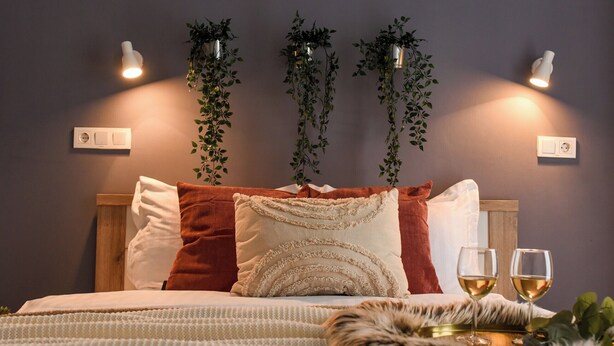 A neatly made bed with decorative pillows, two bedside lamps, and two glasses of wine on a tray. - Urban Heaven in Aviatiei Business Area (Bucharest)